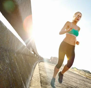 Keeping a steady pace. an attractive young woman out on her morning run. Stock Photos
