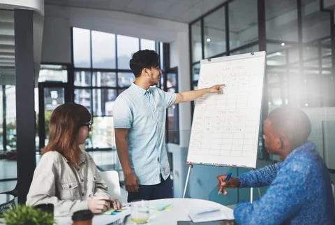 Keeping track of their progress. a young businessman using a whiteboard to give 스톡 사진