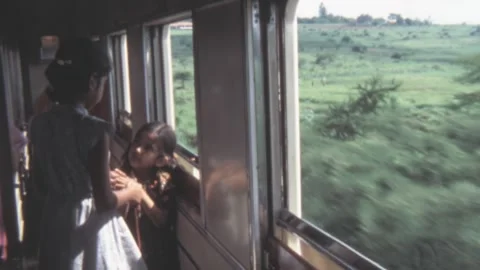 Kenya - 1981: Two Indian girls look out the window of a moving train in Africa Stock Footage 307479224