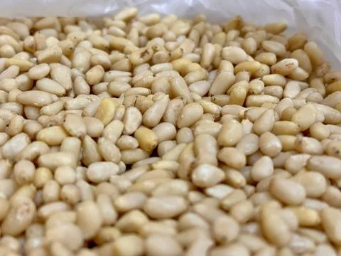 The kernels of peeled pine nuts in a transparent plastic bag for sale by weight Foto stock