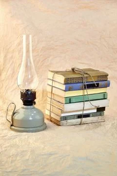 Kerosene lamp and stack of old books tied up with string Stock Photos
