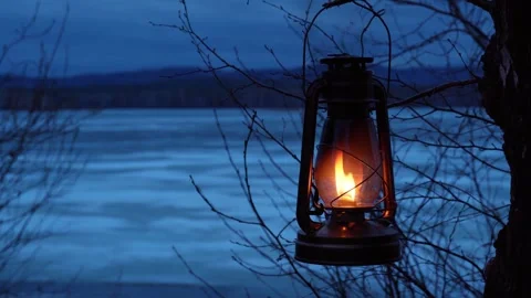 A kerosene lantern hangs on a tree branch and burns with an orange flame. Stock Footage 301701253