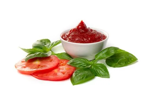 Ketchup (tomato paste) in a saucepan with basil leaves and tomato slices on a Stock Photos