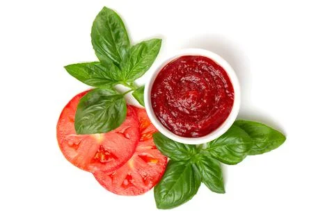 Ketchup (tomato paste) in a saucepan with basil leaves and tomato slices on a Stock Photos