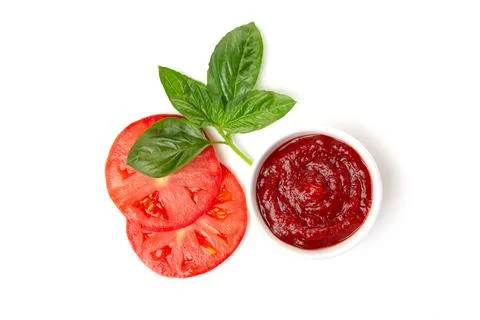 Ketchup (tomato paste) in a saucepan with basil leaves and tomato slices on a Stock Photos