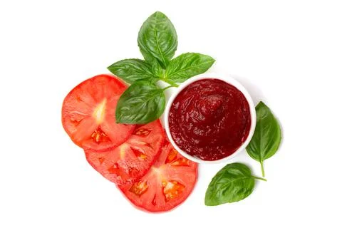 Ketchup (tomato paste) in a saucepan with basil leaves and tomato slices on a Stock Photos