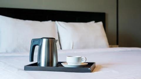 Kettle and a white cup in the bed prepare for a breakfast. Stock Photos