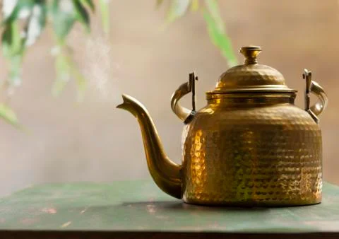 Kettle blowing steam kept on a table outdoor	 Stock Photos