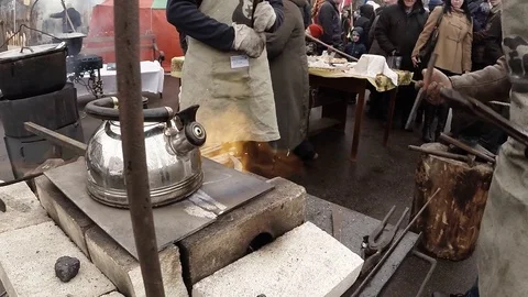 Kettle Boils Near Working Blacksmiths on a Horseshoe on an Anvil Stock Footage 74794003