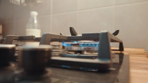 Kettle cools down. Steam fades from lifted kettle. Blue flame dims as kettle is Stock Footage 342339344