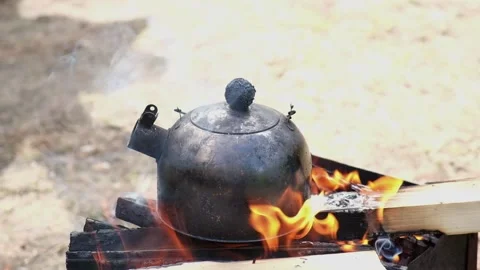 Kettle on the fire in the campaign. Tea party on hike. A soot-black kettle of Stock Footage 230721613
