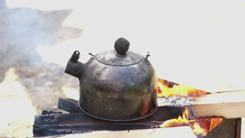 Kettle on the fire in the campaign. Tea party on hike. A soot-black kettle of Stock Footage 231185402
