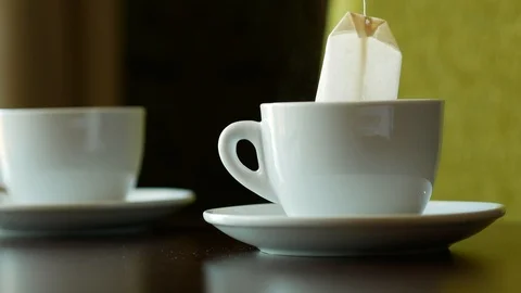 Kettle pouring boiling water into a cup. Brewing tea with bag in hot water. Stock Footage 124499792