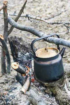 The kettle in the soot over the fire is warming. Stock Photos