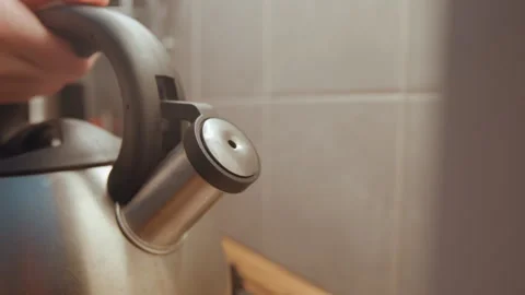 Kettle spout opening. Morning light illuminates gentle steam rise. Hand opening Stock Footage 342336080