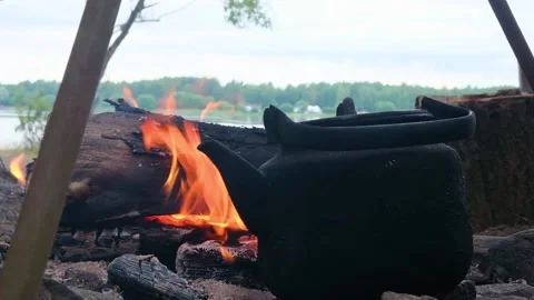 Kettle standing by the fire on a hike against the backdrop of the river. Stock Footage 202717468