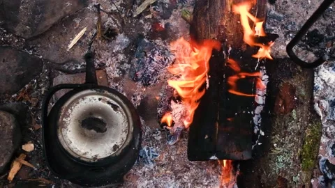 Kettle standing by the fire on a hike against the backdrop of the river. Stock Footage 202717552