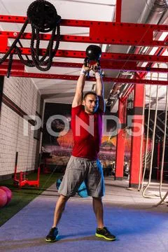 Kettlebell swinging man weightlifting workout gym Stock Photos