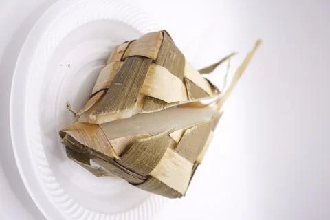 A ketupat that is split in half on a plastic plate, photo taken from the side Stock Photos