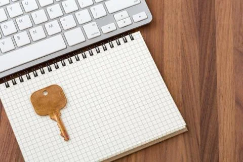 Key on blank notebook with computer keyboard on wooden desk Stock Photos