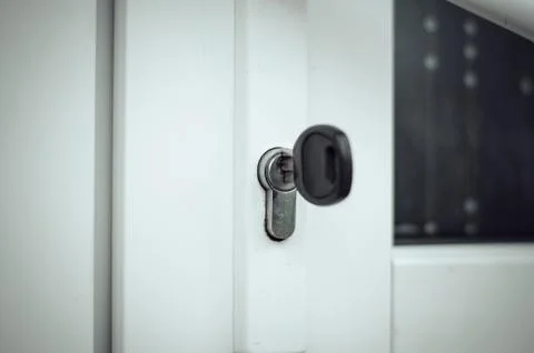 The key is in the door lock of the white front door Stock Photos