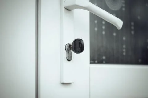 The key is in the door lock of the white front door Stock Photos