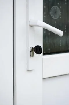 The key is in the door lock of the white front door Stock Photos