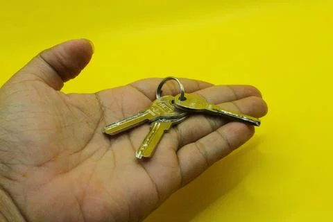Key in hand on a yellow background. The concept of buying or selling real e.. Stock Photos