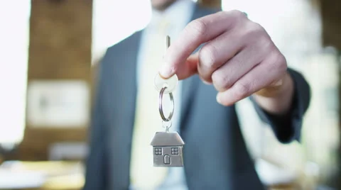 A key is held out with a shiny metallic key fob of a little house Stock Footage 66508857