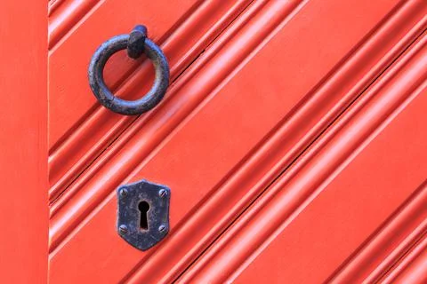 Key hole and ring knocker on a red wooden door with diagonal pattern Stockfoto's