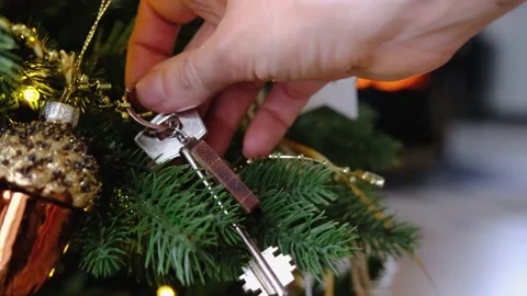 Key to the house with a keychain is hanging in hand on Christmas tree. A gi.. Stock Footage 231036675