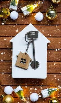 Key to house with a keychain tiny home on wooden background with Christmas .. Stockfoto's