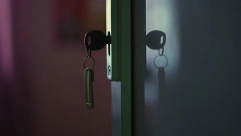 Key is inserted into the lock of the door, indoors, the light from the window Stock Footage 195331566