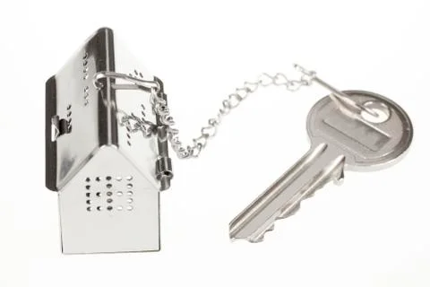 Key with keychain in the form of a silver-colored house on a white background Stock Photos