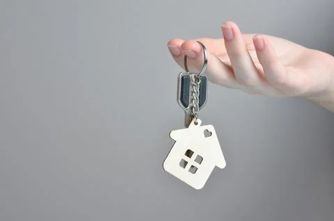 Key with a keychain in the shape of a house in hands. Stock Photos
