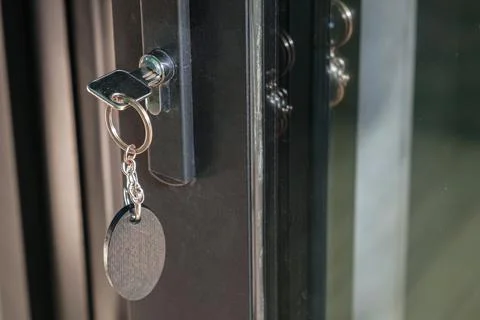 Key with a large oval keychain is inserted into the keyhole Stock Photos