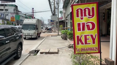 Key locksmith sign storefront on sidewalk outdoor with vehicles moving, Thailand Stock Footage 232963928