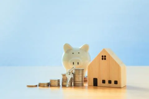 Key placed front of stack coins with model house and piggy bank. mortgage and Stock Photos