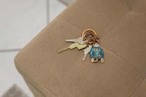 Key ring with earrings on the background of a upholstered furniture Stock Photos