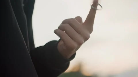 Key ring toy in motion. Closeup of hands twirling key ring during sunset Stock Footage 332368628