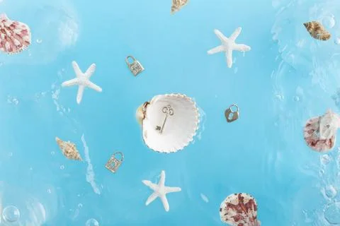 Key in a sea shell and locks in the ocean waves concept Stock Photos