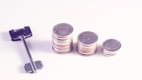 A key is on a table with a pile of coins Stock Photos