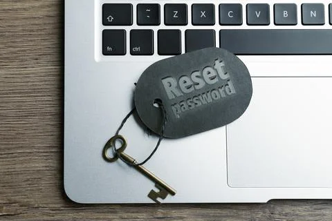Key with tag RESET PASSWORD and laptop on wooden table, top view Stock Photos