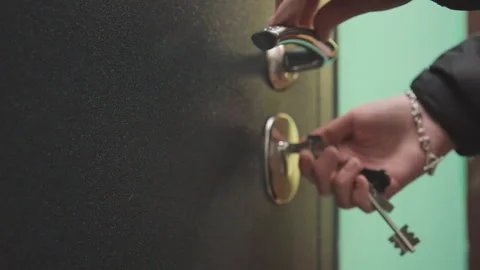 Key turning carefully. Closeup of hand inserting key into lock in quiet setting Stock Footage 346242397