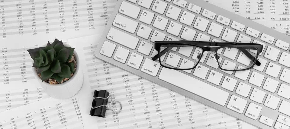 Keyboard and eye glasses lying on financial statement. Top view. Stock Photos
