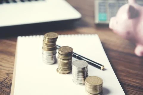 Keyboard with coins on notepad on table Stock Photos