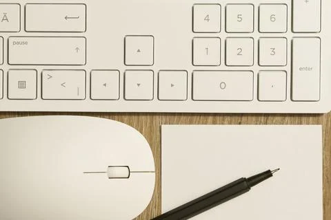 Keyboard from a computer and a computer mouse as well as pen and paper on a desk Stock Photos