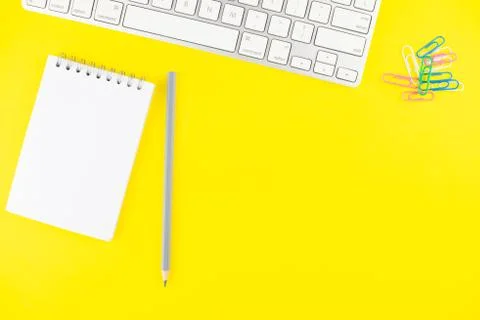 Keyboard, pencil, notepad planner and colorful clips on yellow background. Fl Stock Photos
