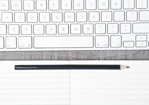 Keyboard with pencil on open notebook sheet on office desk Foto stock