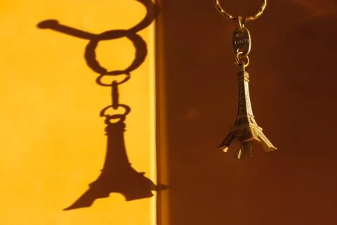 Keychain in the form of the Eiffel Tower and contrast shadow on the wall 스톡 사진